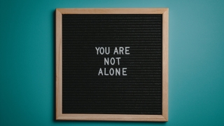 you are not alone quote board on brown wooden frame