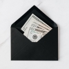 black envelope with cash dollars on marble table