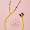 yellow stethoscope and pills on pink background