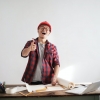 laughing male constructor showing thumb up at working desk